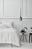A Parisian style bedroom with panelled wall, white floors and white bedding