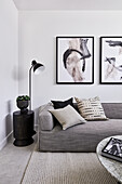 Modern monochrome living room with grey corner sofa, abstract artworks and a marble coffee table