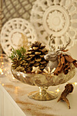 Bowl with golden pine cones, deer and cinnamon as Christmas decoration