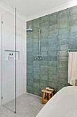 Shower area with green wall tiles and glass partition in the bathroom