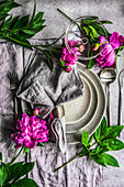 Summer dinner set with peony flowers on the concrete background