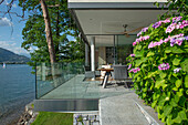 Sunlit terrace with glass balustrade panels by the lake