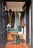 View through open oak door into hallway with coat rack and rubber rain boots