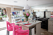 Landhausküche in französischem Stil mit Kücheninsel und pinkfarbenen Barhockern