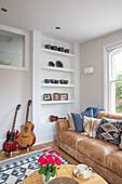 Leather couch, built-in shelves with pottery and guitar in the sitting room