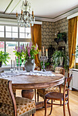 Runder Esstisch mit Blumenstrauß in ländlichem Zimmer mit Tapete