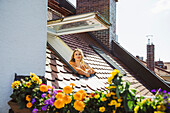 House roof, woman at the open skylight window