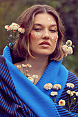 Brünette Frau mit blauem Merino-Kaschmir-Tuch, Blüten und Sternen im Gesicht