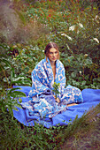 Junge Frau mit blau gemusterter Baumwolldecke und Alpaka-Überwurf in Kobaltblau