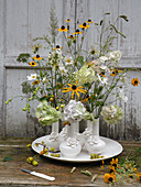Blumenstäuße in weißen Vasen (Sonnenhut, Hortensie und Anemone)