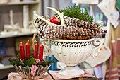 Baking tin with four red candles and metal bowl of pine cones