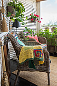 Cozy wicker chairs with crocheted blanket on the terrace
