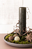 Weihnachtsarrangement mit Kalenderkerze und mit DIY-Perlenkugeln auf Teller mit Moos