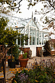 Blick auf Gewächshaus mit Backsteinsockel im herbstlichen Garten