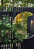 Zaun mit rundem Spiegel im Garten
