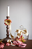 Fabric ribbon with artificial blossoms around candle holder