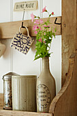 Wooden shelf with cut flowers in ceramic bottle and cup