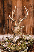 Silver deer head in a wreath in front of a vintage wooden wall