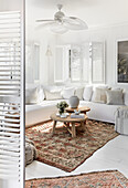 Weiße Sitzmöbel mit Leinenbezug, Fensterläden und marokkanische Teppiche im Wohnzimmer