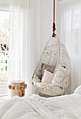 Bed with white bed linen and hanging chair in the bedroom