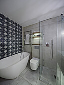 Freestanding bathtub in front of patterned wall tiles and shower area in bathroom