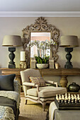 Custom upholstered furniture in the elegant living room with large wooden console table and ornate mirror