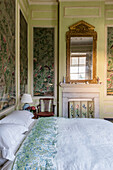 Oriental wall panels and mirror with gold frame in the bedroom of a 17th century English country house.