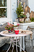 Candles and berries on a round table, bench, and chest of drawers with Christmas decorations on the terrace