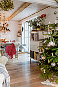 Weihnachtlich dekorierter Wohnraum mit geschmücktem Tannenbaum im Vordergrund