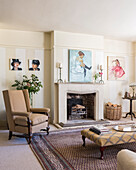 James Wedge artwork on walls of sitting room with regency style ottoman, oriental rug and limestone fire surround