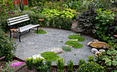 Oval gravel area with a bench in the garden