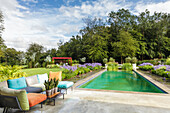 Buntes Outdoorsofa am Pool mit Schmucklilien im luxuriösen Garten