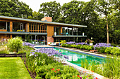 Blumenbeete um den Pool im Garten um luxuriöses Architektenhaus