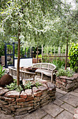 Paved patio with wooden benches, silver pear tree in raised bed made of dry stone wall