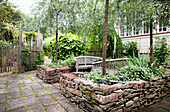 Paved patio with wooden benches and dry stone wall raised beds