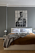 Doppelbett, darüber Kunstwerk im Schlafzimmer mit grauer Wand