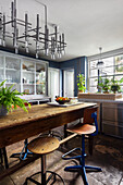 Industrial table with vintage stools, above it modern lamp in the kitchen