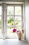 Pfingstrosen in dekorativem Topf auf Fensterbank
