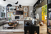 Living room with black mobile and artwork hung on a brick wall, passage framed by black shelf