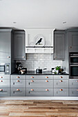 Open kitchen with grey cabinet fronts and white tiled backsplash