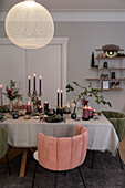 Festively laid Christmas table with candles, velvet upholstered chairs around the table