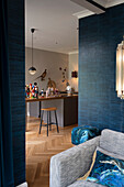 Blick vom Wohnzimmer mit blauer Tapete in weihnachtlich dekorierte Küche