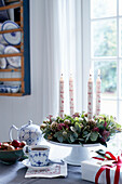 Advent wreath made of leafy branches and skimmia with candles on an etagere