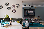Fornasetti decorative plates hung on the wall in the dining area, living room with elegant sofa in the background
