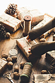 Christmas gifts, roll of yarn, walnuts and cones on wooden table