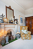 Decommissioned fireplace with eclectic collection and wing chair with flowered cover