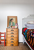 Antique dresser as a night stand with portrait painting in the guest room