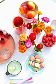 Colorful late summer flowers, raspberries, macarons, and candles on table