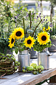 Bouquet of sunflowers and poppy capsules in milk cans