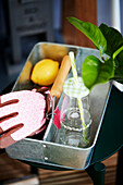 Trinkflasche, Gartenwerkzeug, Zitrone und Handschuh im Behälter